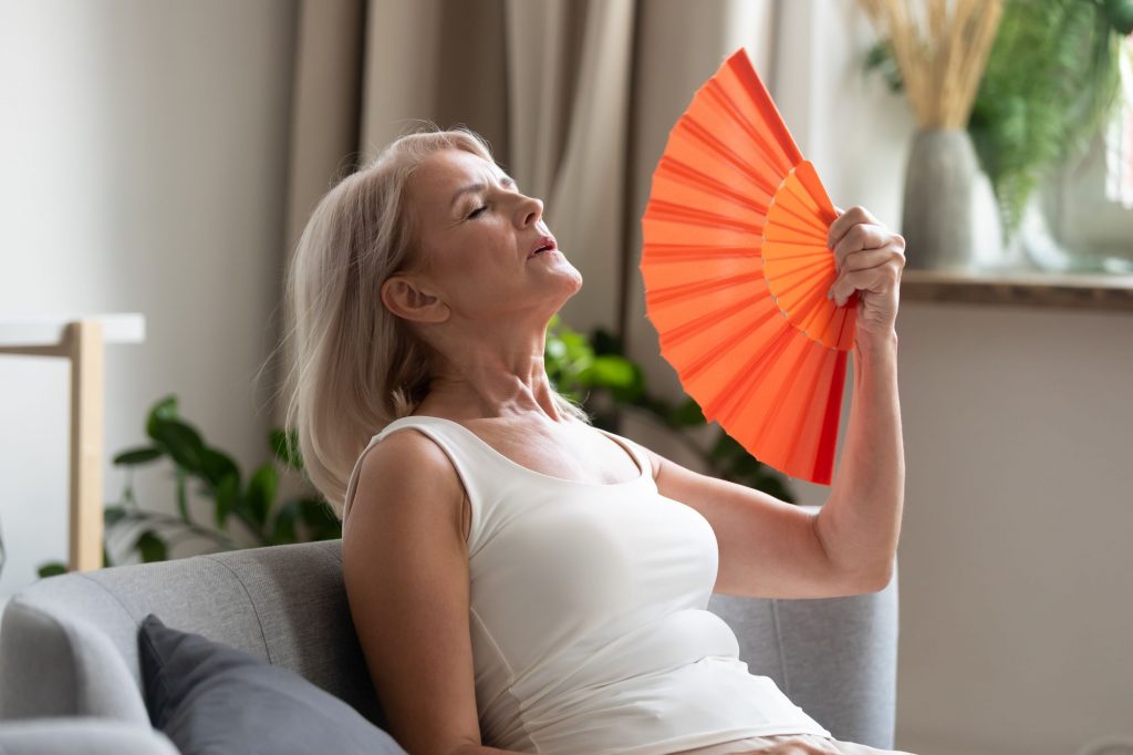 Older woman using a fan to cool down